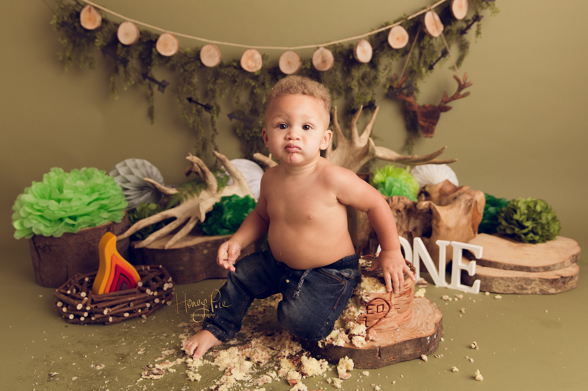 Baby boy sitting on his birthday cake during cake smash photoshoot in Worthing