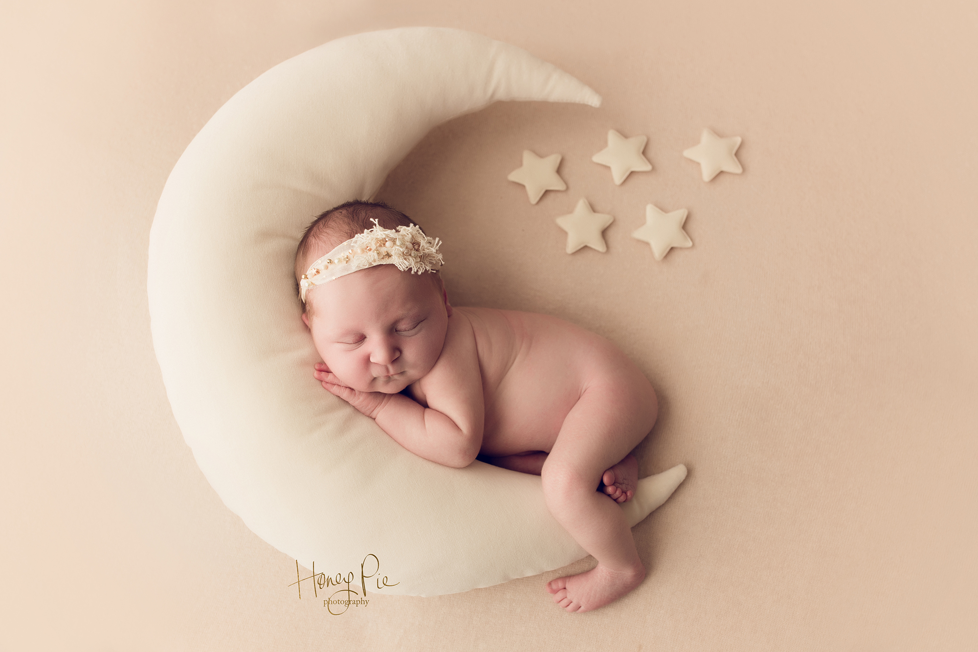 Newborn baby girl sleeping cuddled into a large moon pillow during west sussex newborn photoshoot