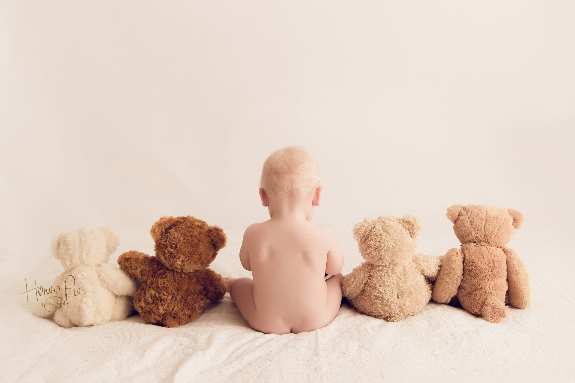 baby boy sitting with his back to the camera with 4 teddy bears during his baby photoshoot in brighton