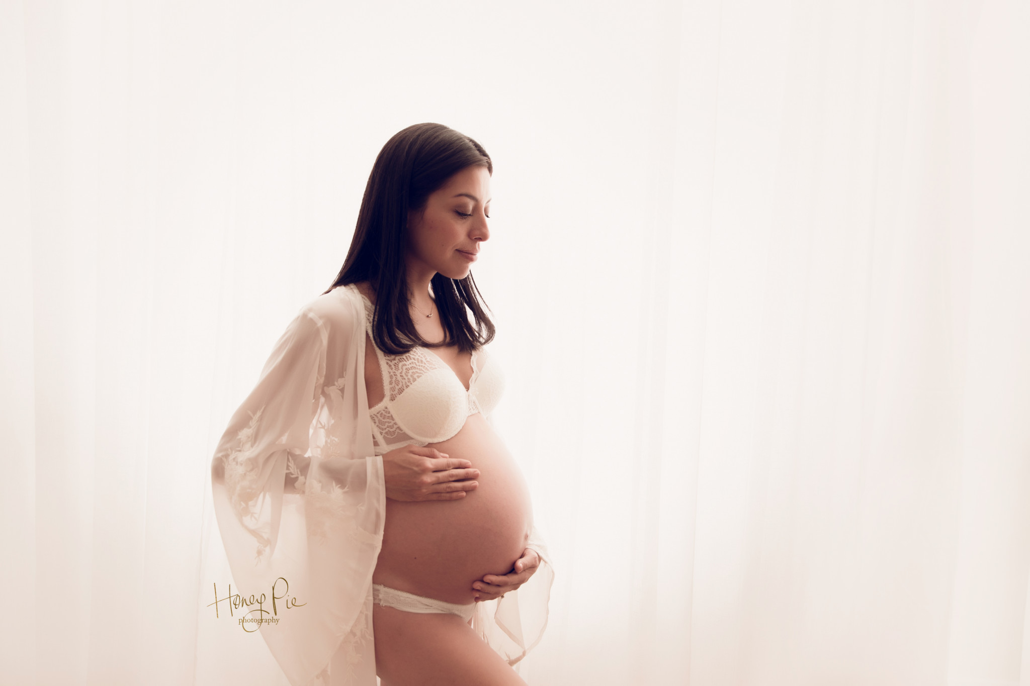 Pregnant woman holding her beautiful baby bump smiling softly with eyes closed