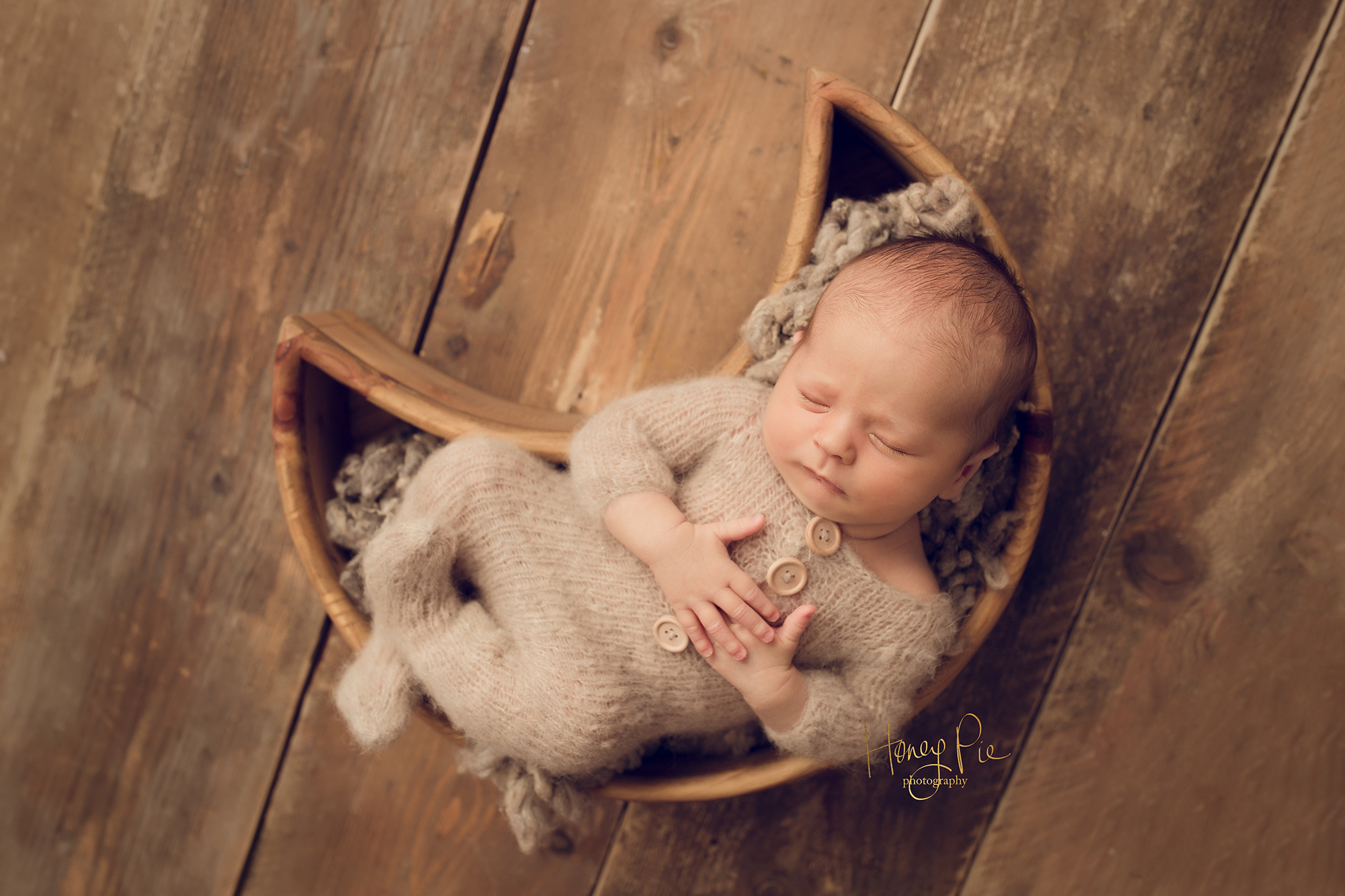 Baby boy fast asleep in a moon at a photoshoot wearing a fluffy soft romper suit