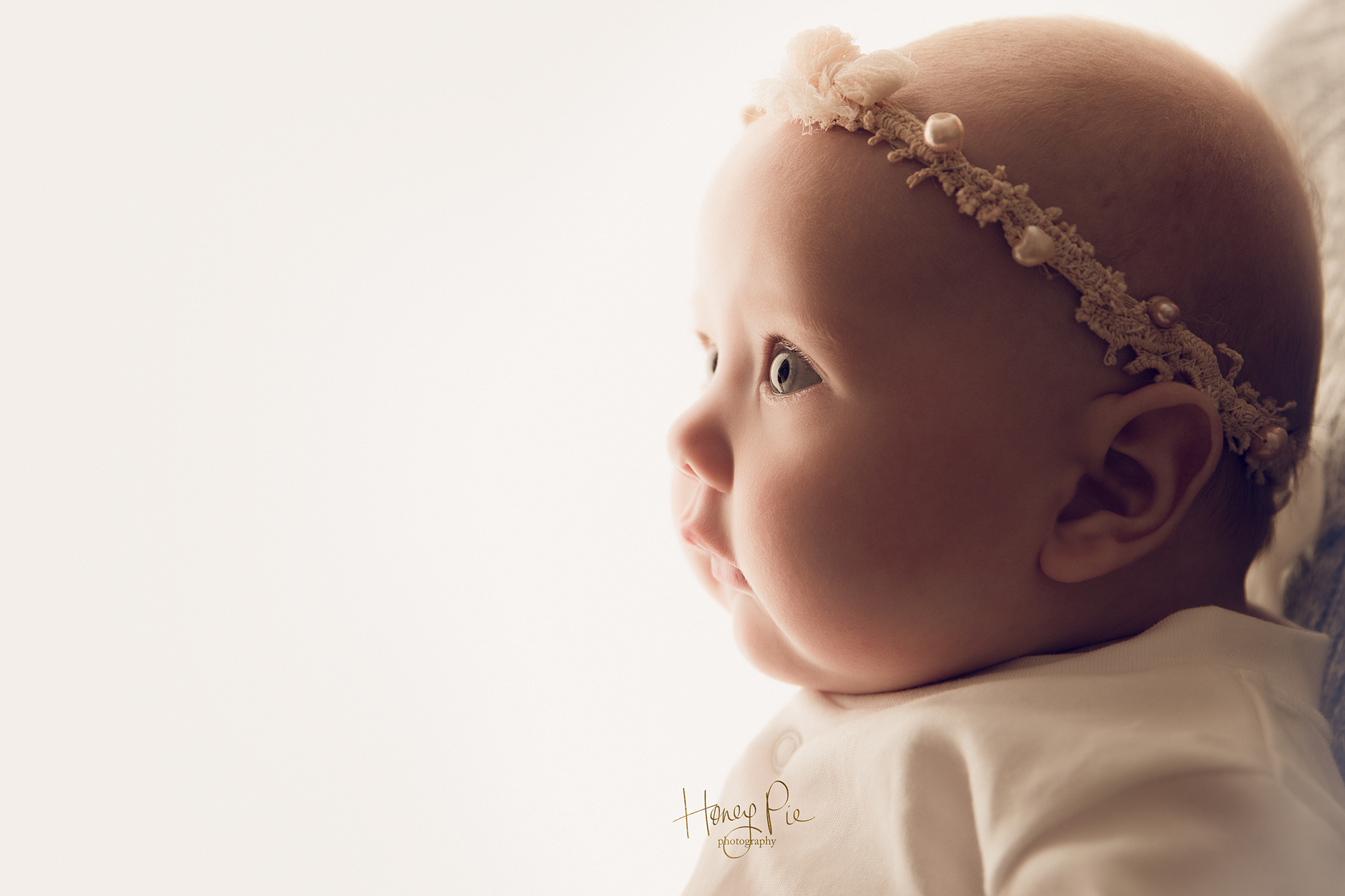 Little baby girl gazing off into the distance showing her beautiful sparkly eyes image taken by her baby photographer sussex