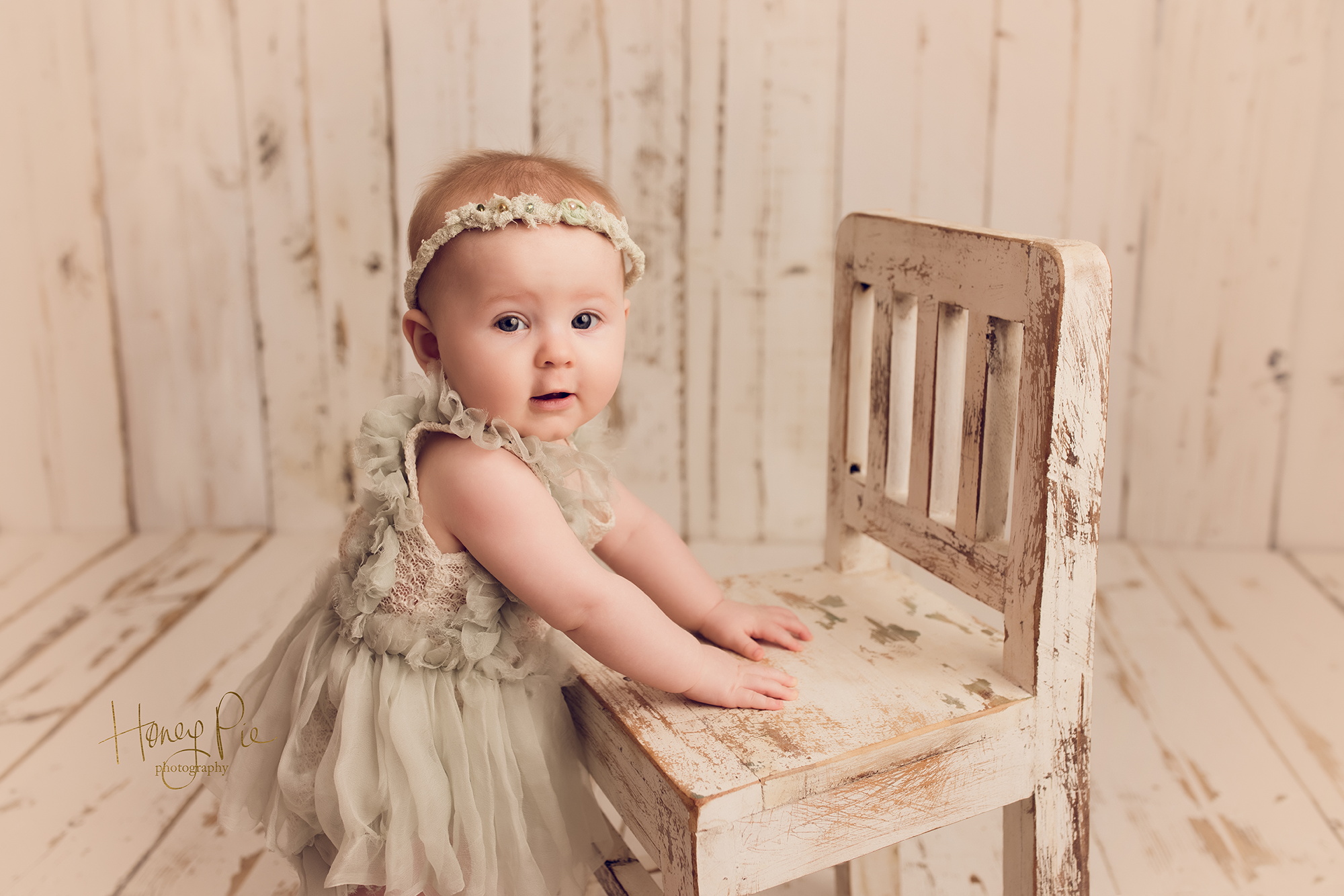 9 month old with wide eyes smiling at photographer during her baby photoshoot in sussex